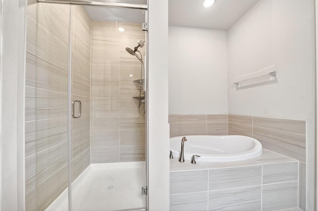 1810 Rhea Court Celina, TX 75009 - Photo 11 of 32 The bathroom features a spacious shower with glass enclosure and light-toned tilework, alongside a built-in bathtub with coordinating tile surround