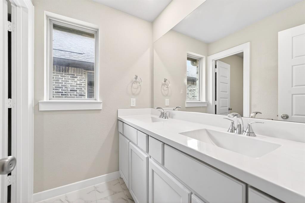 1810 Rhea Court Celina, TX 75009 - Photo 18 of 32 The bathroom features a large vanity with two integrated sinks and chrome faucets, set against a light-colored countertop