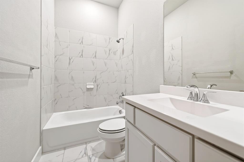 1810 Rhea Court Celina, TX 75009 - Photo 22 of 32 Well-appointed bathroom featuring a clean white vanity with an integrated sink and chrome faucet, a bathtub, and a toilet