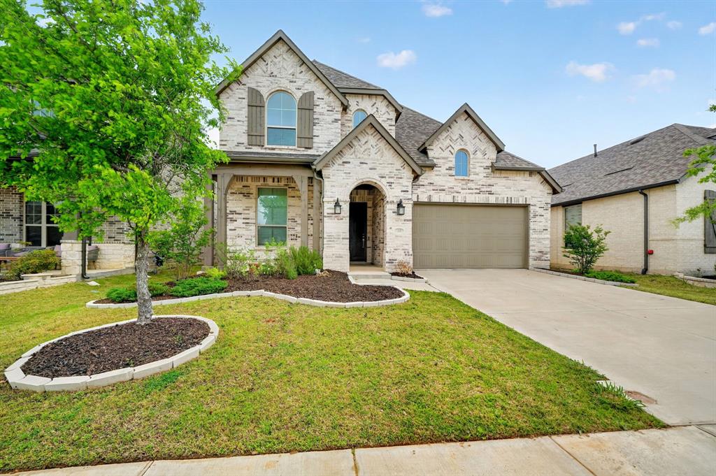 1810 Rhea Court Celina, TX 75009 - Photo 3 of 32 This property showcases a brick exterior with dark trim and shutters, featuring a prominent arched entry and an attached garage