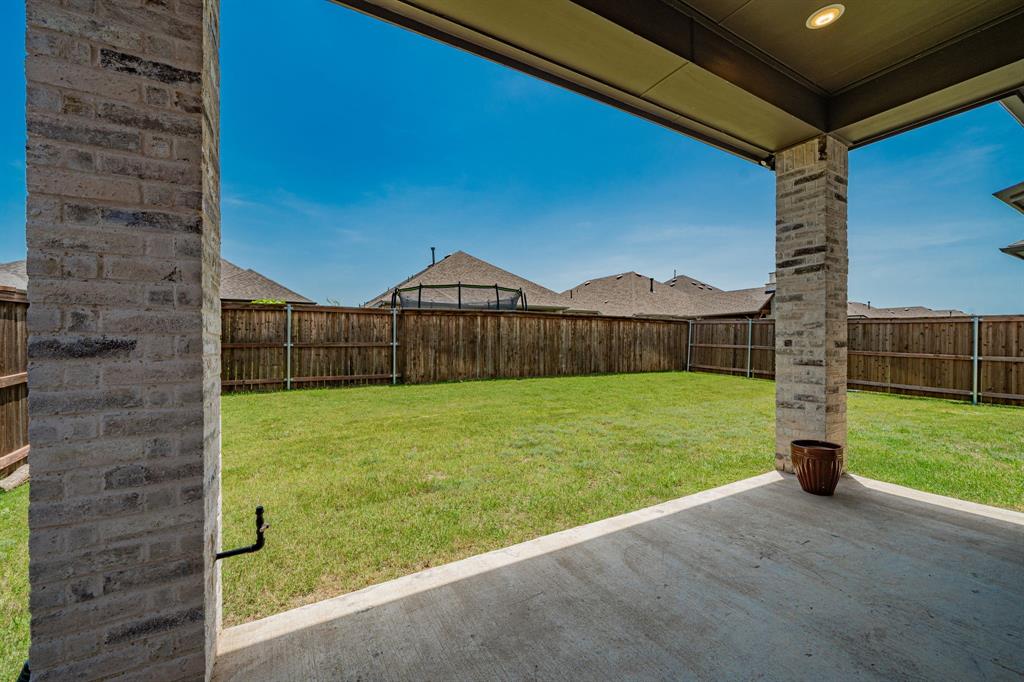 1810 Rhea Court Celina, TX 75009 - Photo 31 of 32 The property features a covered patio with brick pillars and a concrete surface, overlooking a spacious lawn