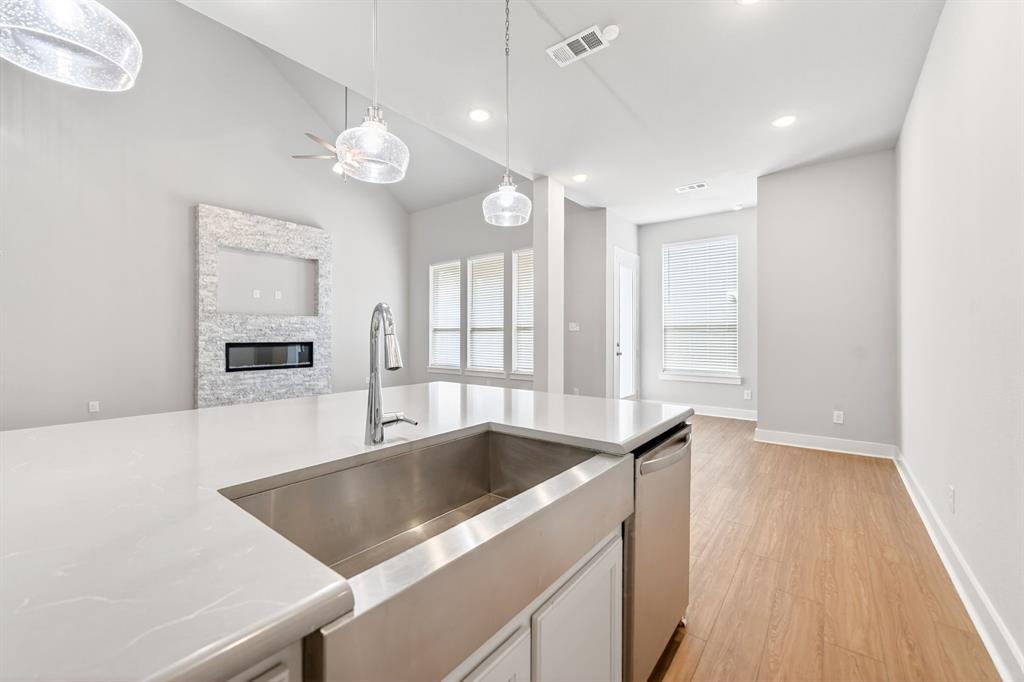 1810 Rhea Court Celina, TX 75009 - Photo 6 of 32 The kitchen features a large island with a stainless steel sink and a contemporary faucet, complemented by modern pendant lighting