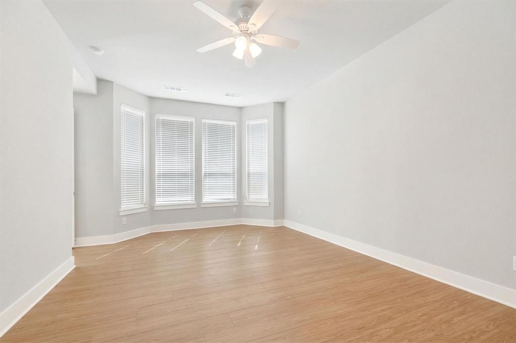 1810 Rhea Court Celina, TX 75009 - Photo 8 of 32 The property features light wood flooring, a ceiling fan, and a bay window configuration with white blinds