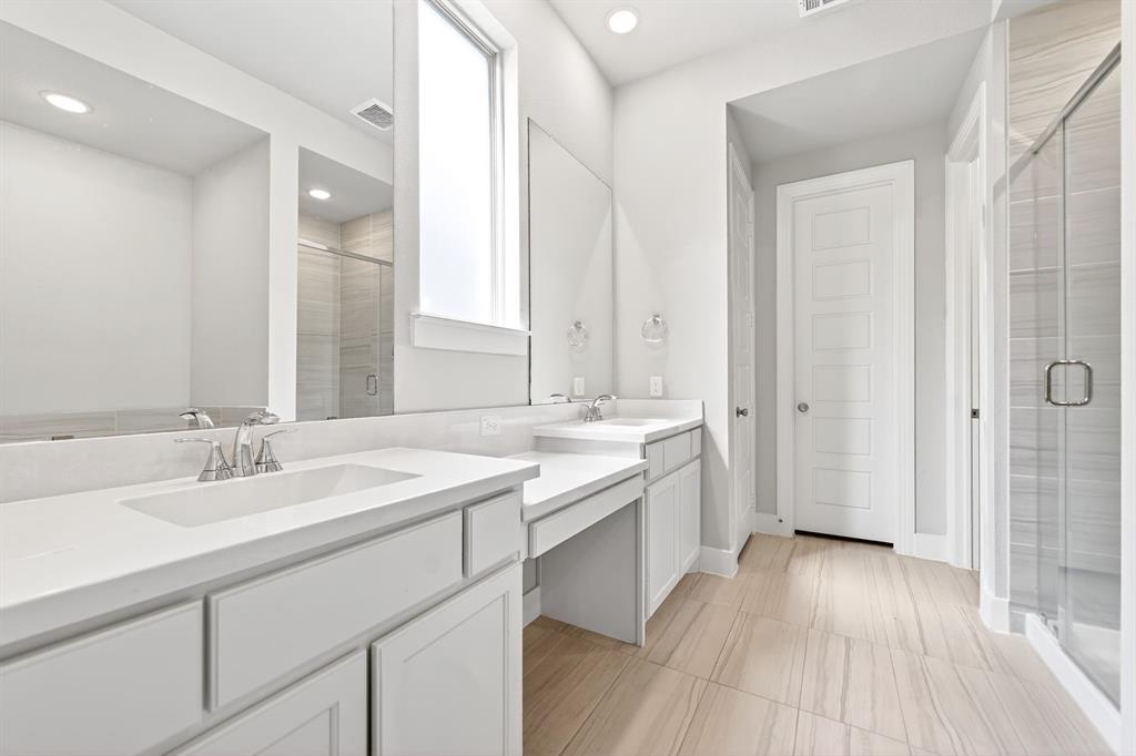 1810 Rhea Court Celina, TX 75009 - Photo 10 of 32 This bathroom features dual vanities with white countertops and sinks, a spacious glass-enclosed shower, and light-toned floor tiling