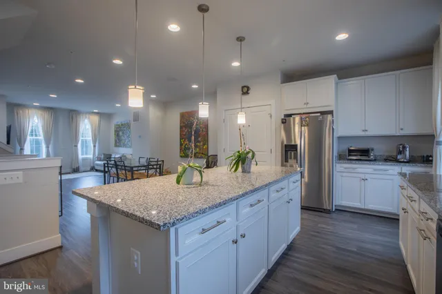 a kitchen with stainless steel appliances granite countertop kitchen island wooden cabinets and refrigerator