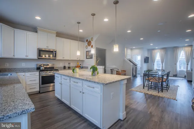 a kitchen with stainless steel appliances granite countertop a stove top oven a sink dishwasher a dining table and chairs with wooden floor