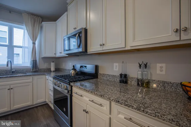 a kitchen with granite countertop white cabinets and a stainless steel appliances