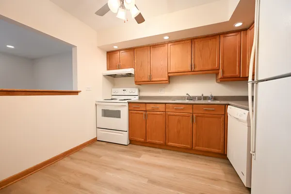 a kitchen with stainless steel appliances granite countertop a stove a sink and white cabinets with wooden floor