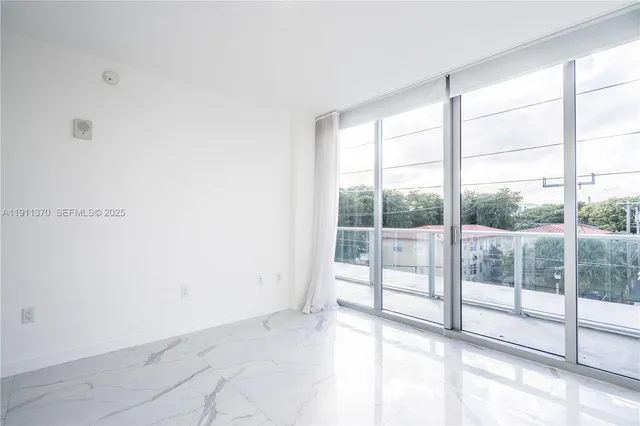 a view of an empty room with wooden floor and windows