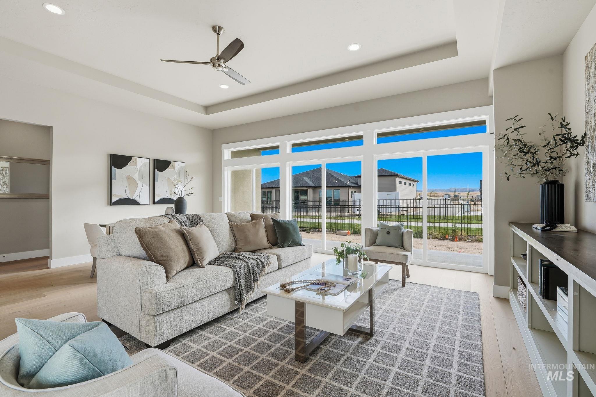 470 South Radiator Way Boise, ID 83716 - Photo 8 of 50 Living area featuring expansive windows, tray ceiling with recessed lighting, wood-finish flooring, a ceiling fan, and built-in shelving