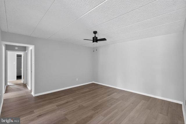 a view of a room with wooden floor and a ceiling fan