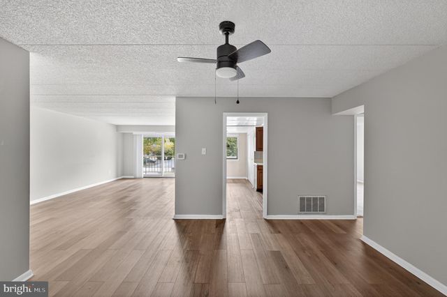 a view of empty room with wooden floor and ceiling fan