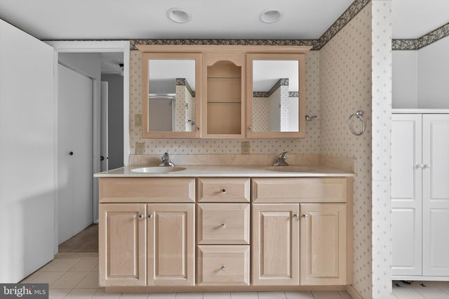 a bathroom with a granite countertop double vanity sink and mirror