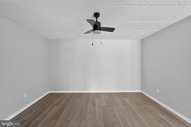 a view of a room with wooden floor and ceiling fan