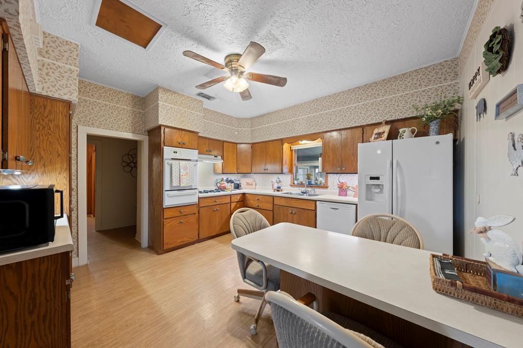 133 Myrtle Avenue Harper, TX 78631 - Photo 6 of 25 a kitchen with a table chairs refrigerator and microwave