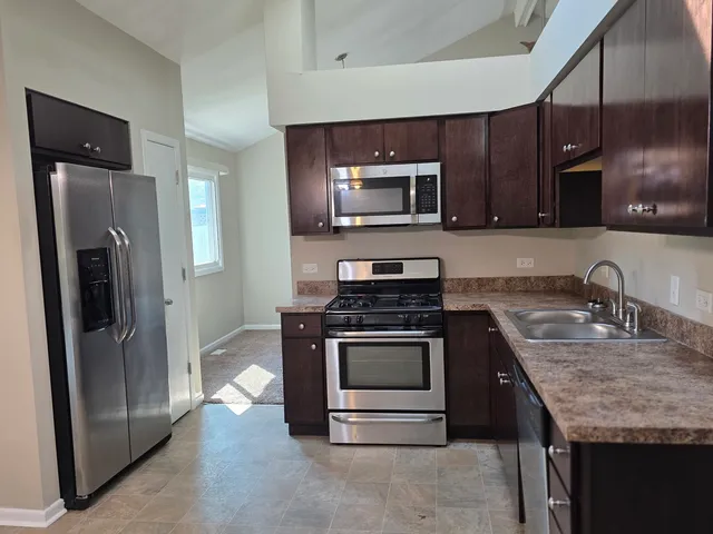 a kitchen with granite countertop a refrigerator stove and microwave