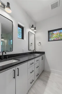 a bathroom with a granite countertop double vanity sink and a mirror