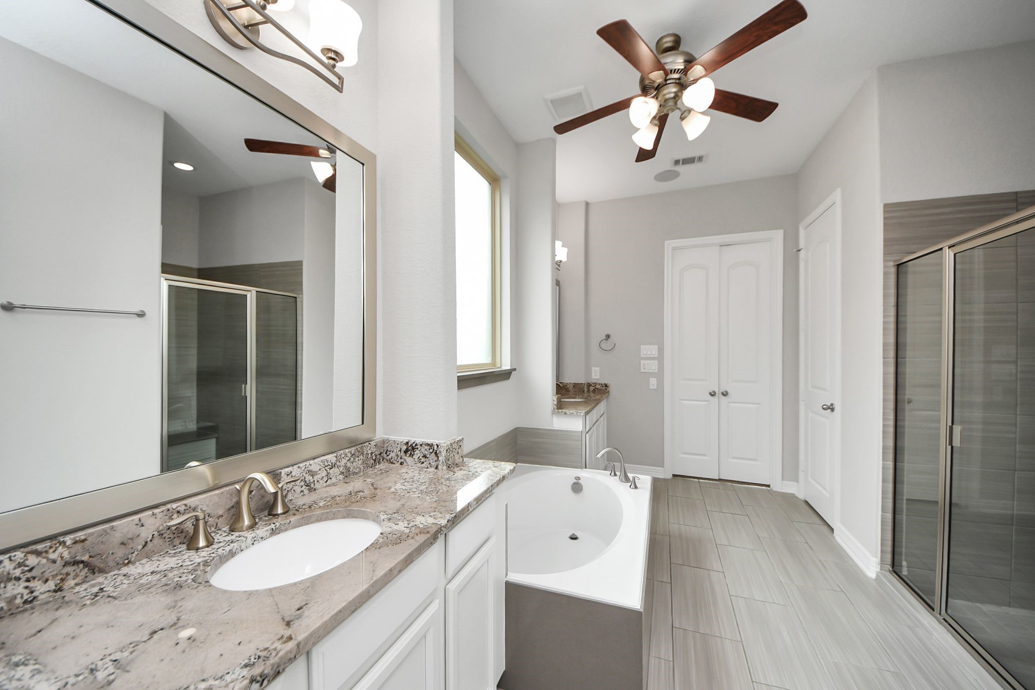 6002 Granite Shadow Lane Houston, TX 77365 - Photo 24 of 49 a spacious bathroom with a granite countertop sink a light fixture and a mirror