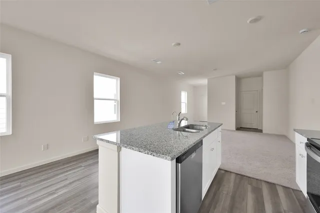 a kitchen with stainless steel appliances granite countertop a stove top oven a sink dishwasher and a refrigerator with wooden floor