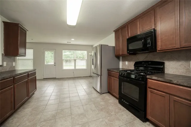 a kitchen with granite countertop a stove top oven microwave and cabinets