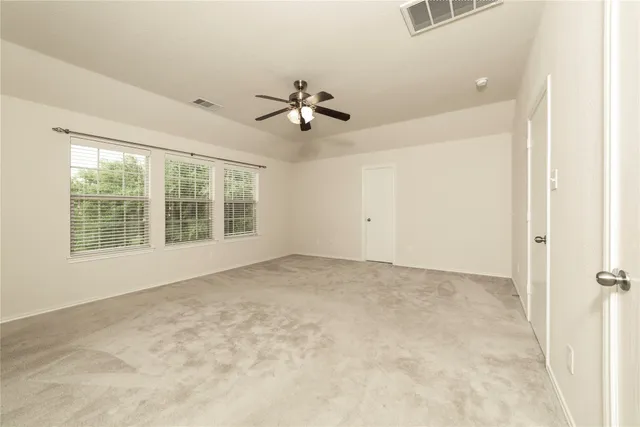 an empty room with windows and fan