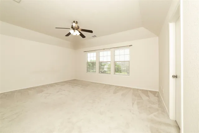 an empty room with chandelier fan and windows