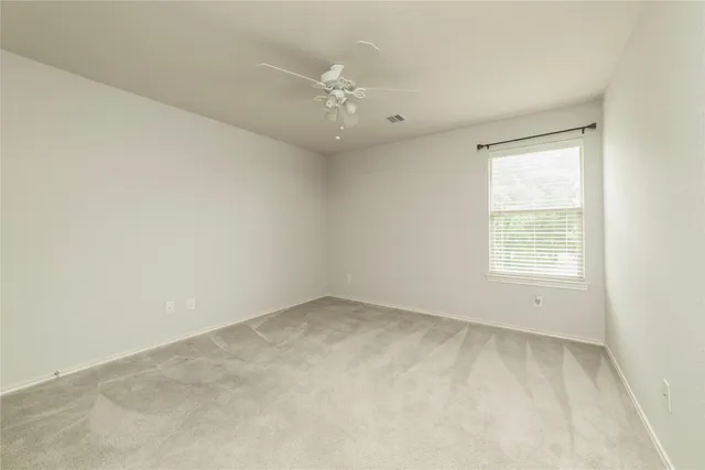 an empty room with chandelier fan and windows