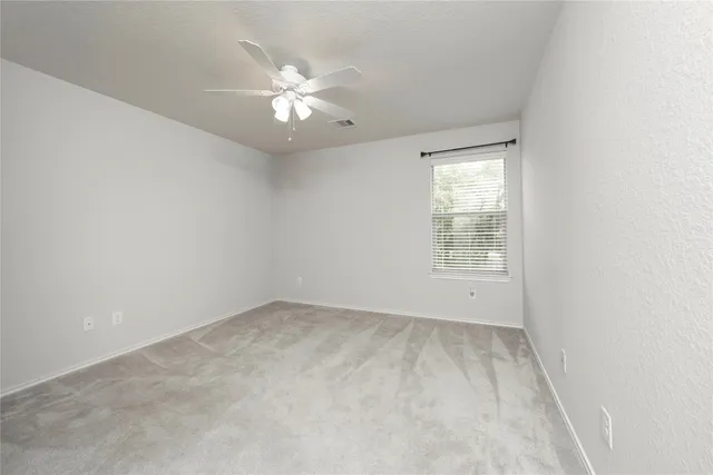 an empty room with windows and chandelier fan