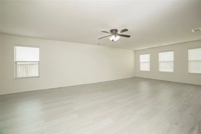 an empty room with windows and ceiling fan