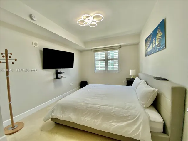 a bedroom with a bed and a flat tv screen on wall