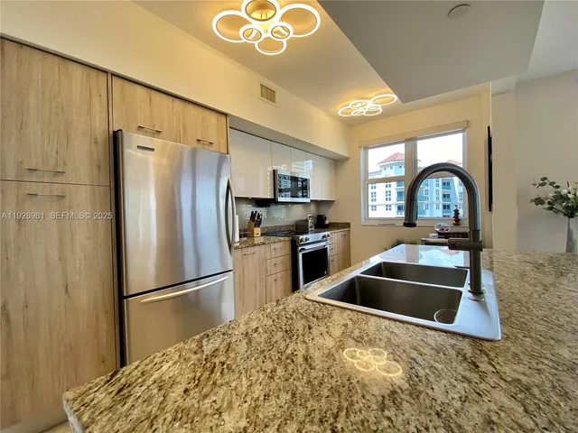 a kitchen with granite countertop a refrigerator and a sink