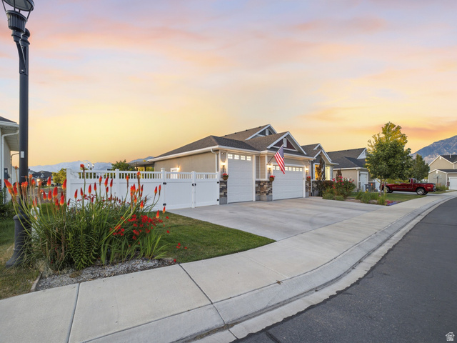 7 Sterling Loop Vineyard, UT 84059 - Photo 38 of 43 Single-story residence featuring a two-car garage with overhead doors, stacked stone accents on the facade, and a white privacy fence