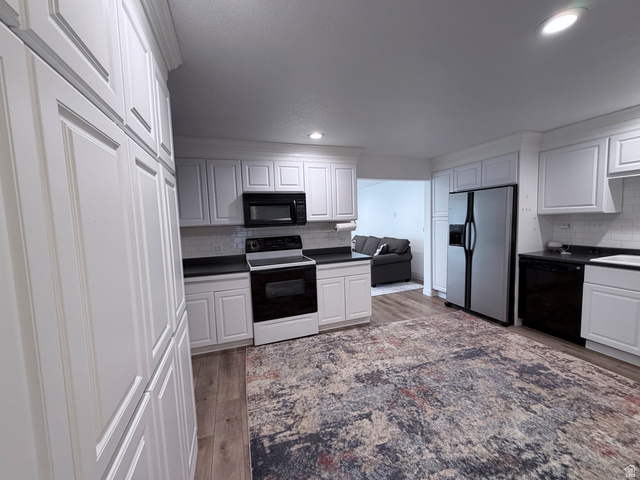 2855 South 1000 West Perry, UT 84302 - Photo 139 of 142 Kitchen with black appliances, white cabinetry, light wood-style flooring, tasteful backsplash, and recessed lighting