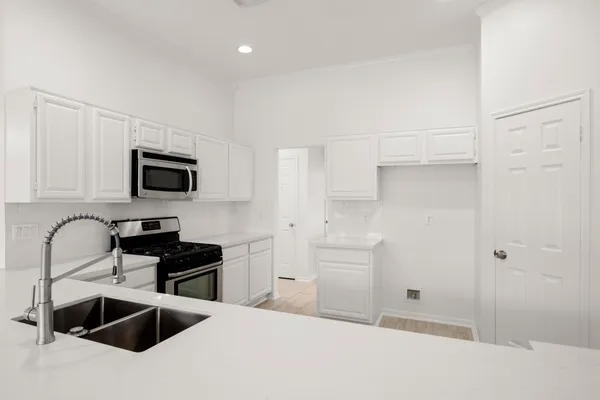 a kitchen with granite countertop a sink and a stove top oven with white cabinets