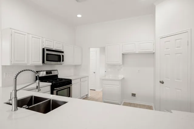 a kitchen with granite countertop a sink and a stove top oven with white cabinets