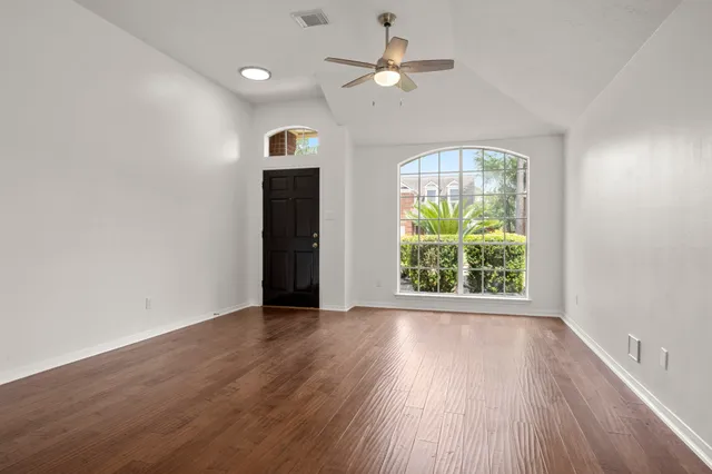 an empty room with wooden floor chandelier and fan