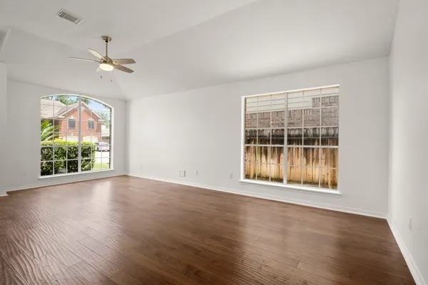 a view of an empty room with wooden floor and a window