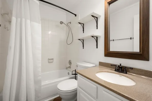 a bathroom with a granite countertop sink toilet a mirror and shower