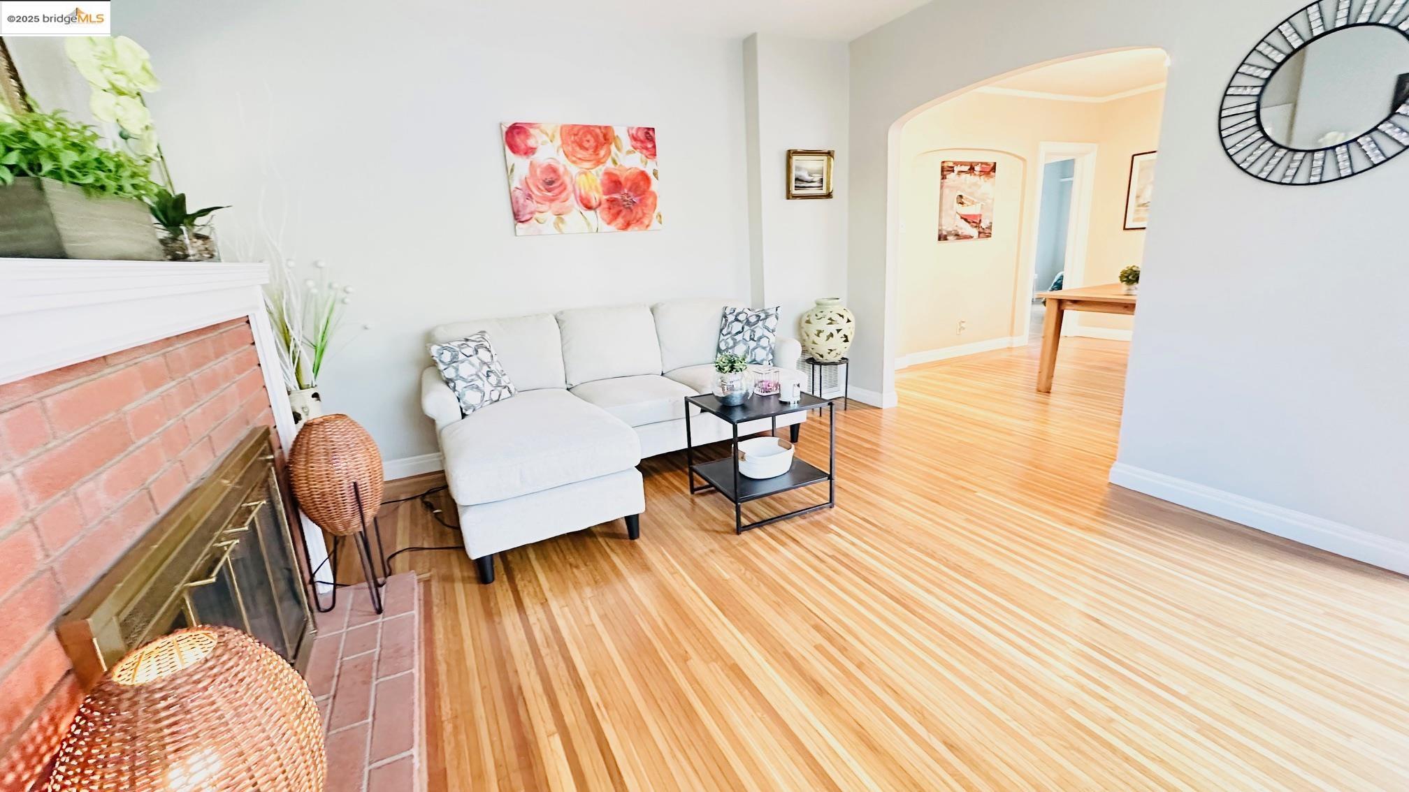 840 Key Rte Boulevard Albany, CA 94706 - Photo 8 of 29 Living area featuring arched walkways, light wood-type flooring, a fireplace, and crown molding