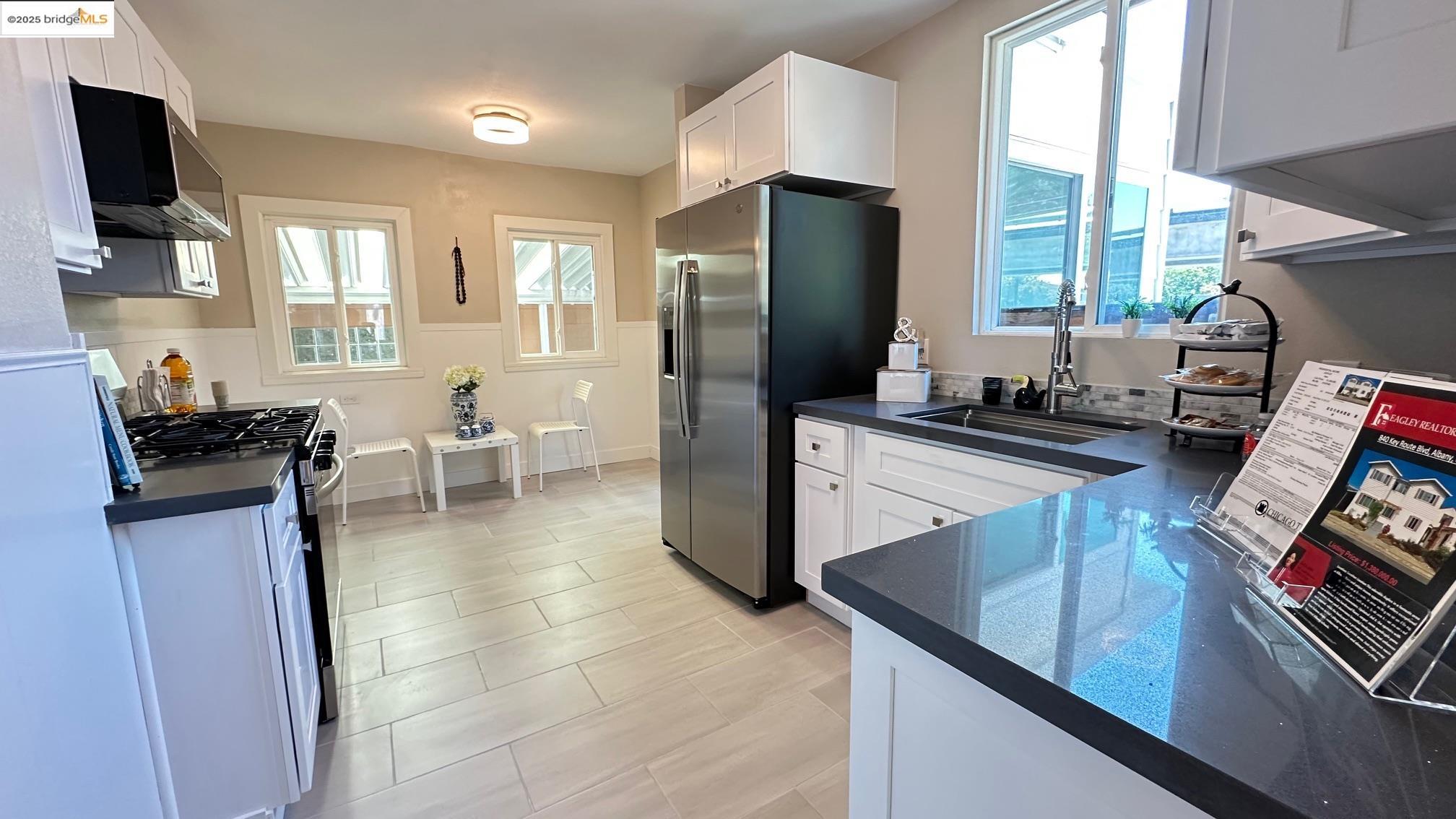 840 Key Rte Boulevard Albany, CA 94706 - Photo 10 of 29 Kitchen featuring white cabinetry, appliances with stainless steel finishes, range hood, and dark stone counters