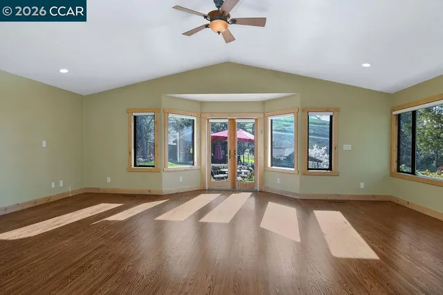 a view of empty room with wooden floor and fan