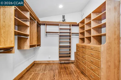 an empty room with wooden floor and a ceiling fan