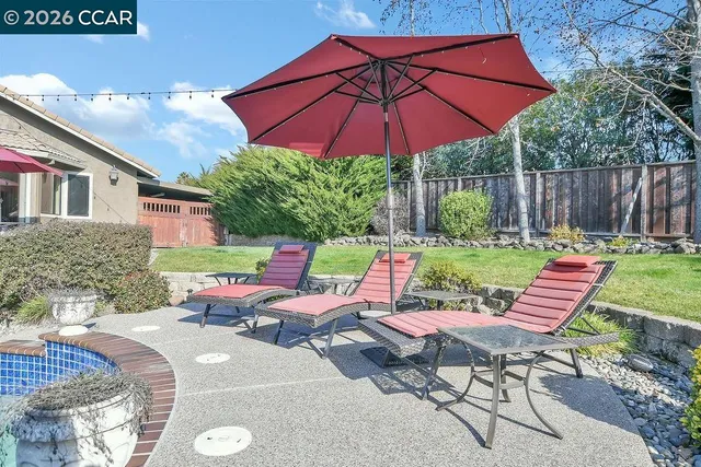a view of a patio with couches table and chairs under an umbrella