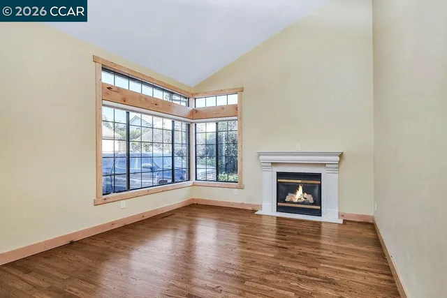 a view of empty room with wooden floor and fireplace
