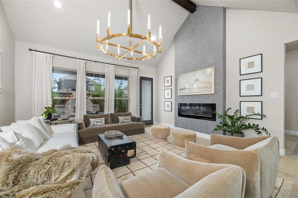 2262 Poppyvine Road Frisco, TX 75033 - Photo 2 of 40 Spacious living area featuring a vaulted ceiling with an exposed beam, a modern linear fireplace with a textured surround, a large brass chandelier, and multiple windows with white drapery