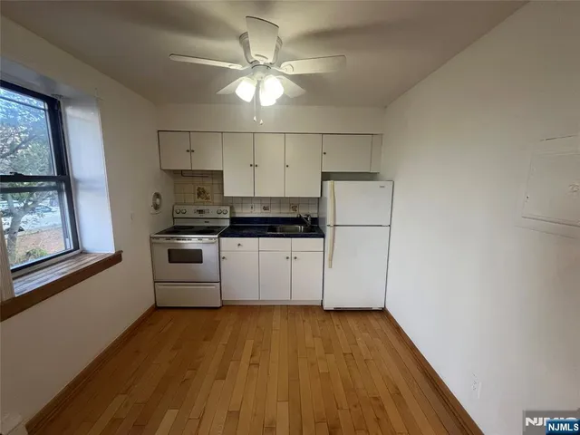 a kitchen with stainless steel appliances a white refrigerator a stove a microwave and white walls