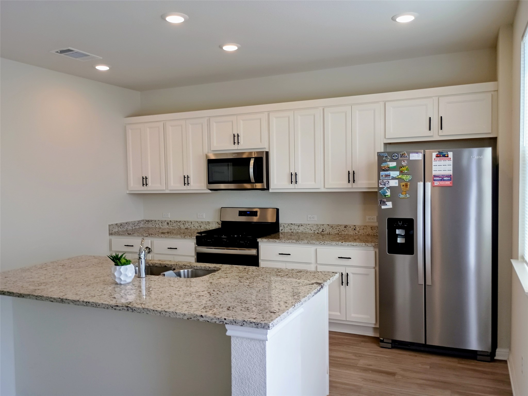 10615 Ridan Way Buda, TX 78610 - Photo 4 of 21 Kitchen with stainless steel appliances, white cabinets, light stone countertops, light wood-style flooring, and recessed lighting