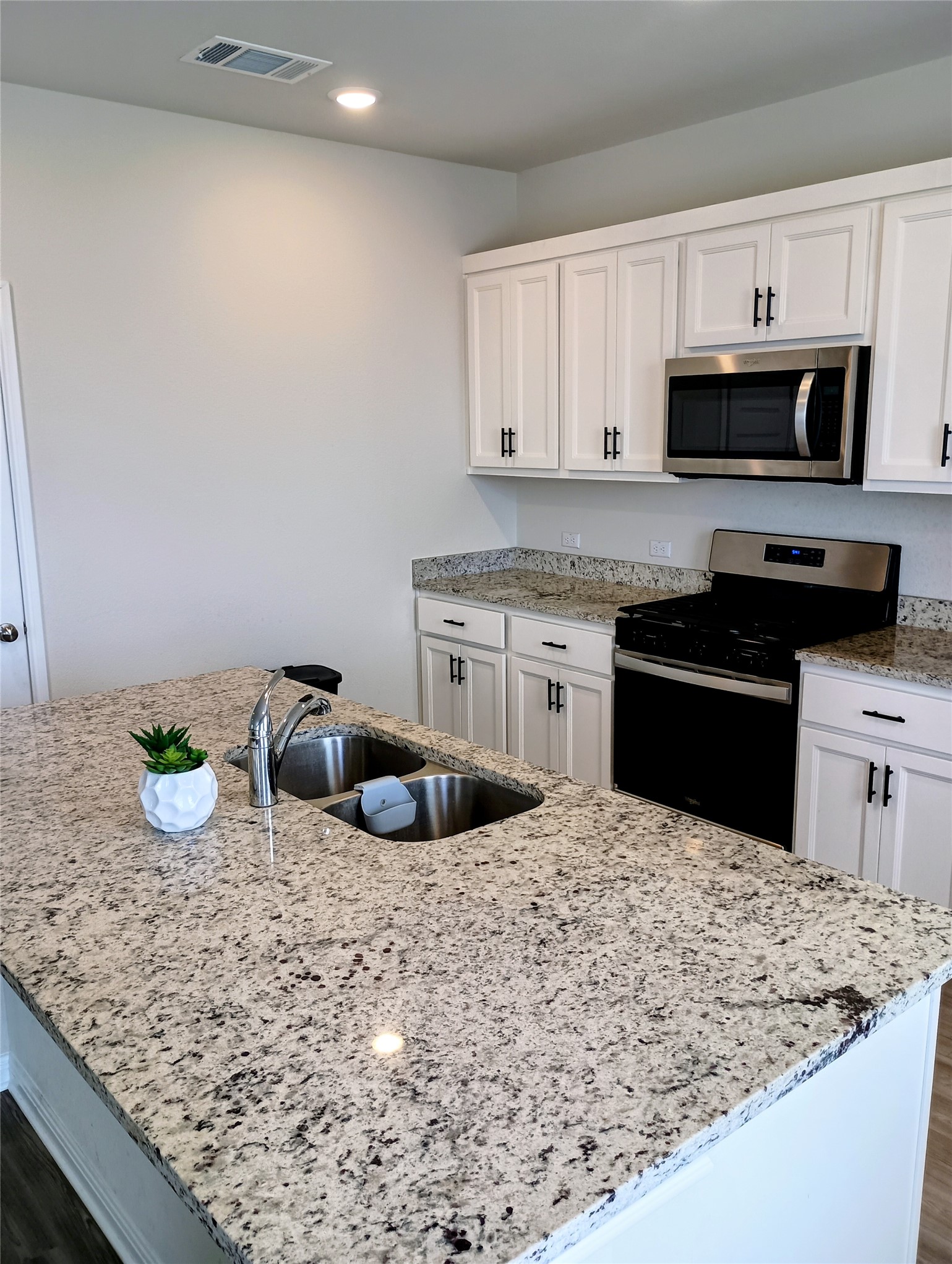 10615 Ridan Way Buda, TX 78610 - Photo 6 of 21 Kitchen with gas range oven, stainless steel microwave, white cabinetry, light stone countertops, and recessed lighting