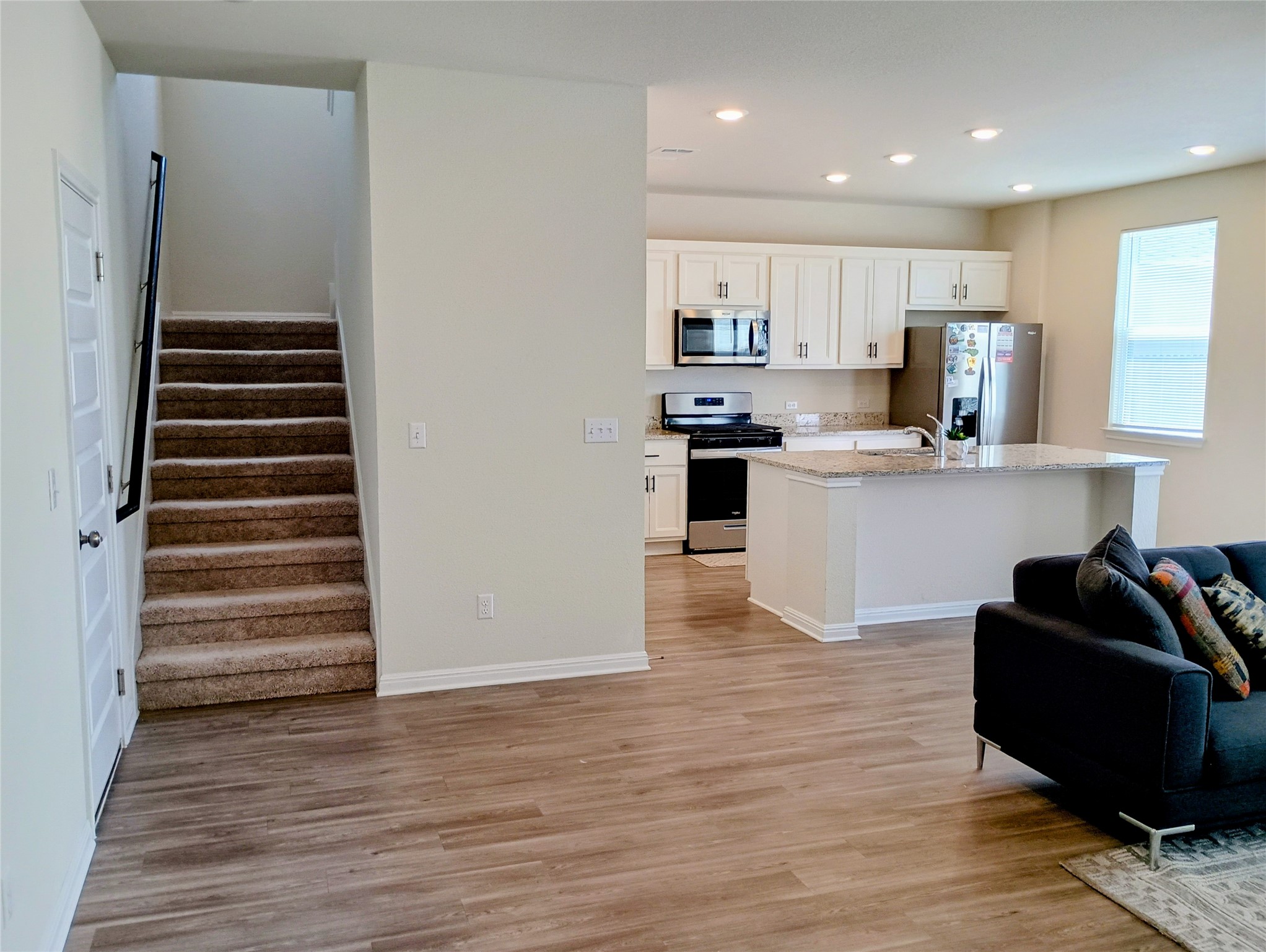 10615 Ridan Way Buda, TX 78610 - Photo 21 of 21 Kitchen with stainless steel appliances, white cabinets, open floor plan, a kitchen island with sink, and light wood finished floors