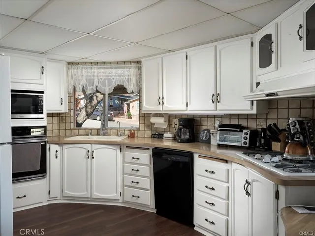 a kitchen with granite countertop white cabinets and stainless steel appliances
